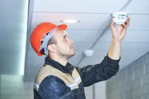 worker installing smoke detector on the ceiling